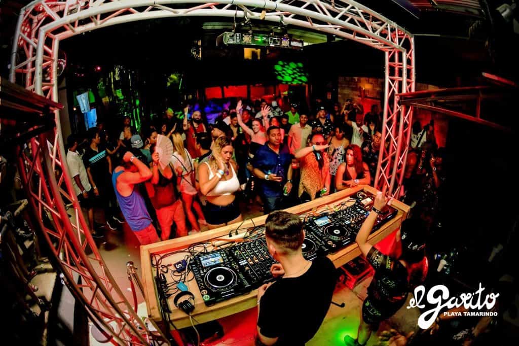 Party scene at Tamarindo beach club with DJ and dancing crowd.