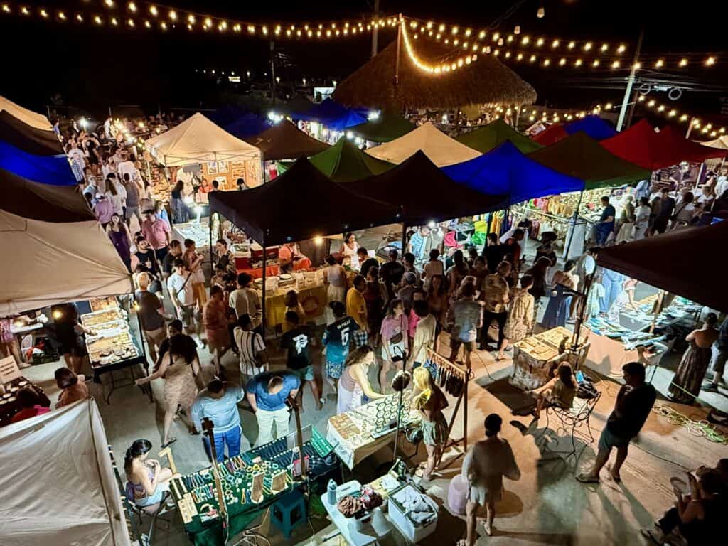 Crowds walking between tents and string lights at the Tamarindo night market