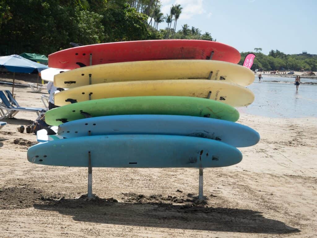 Stack of colorful rental surfboards on a rack on Tamarindo Beach