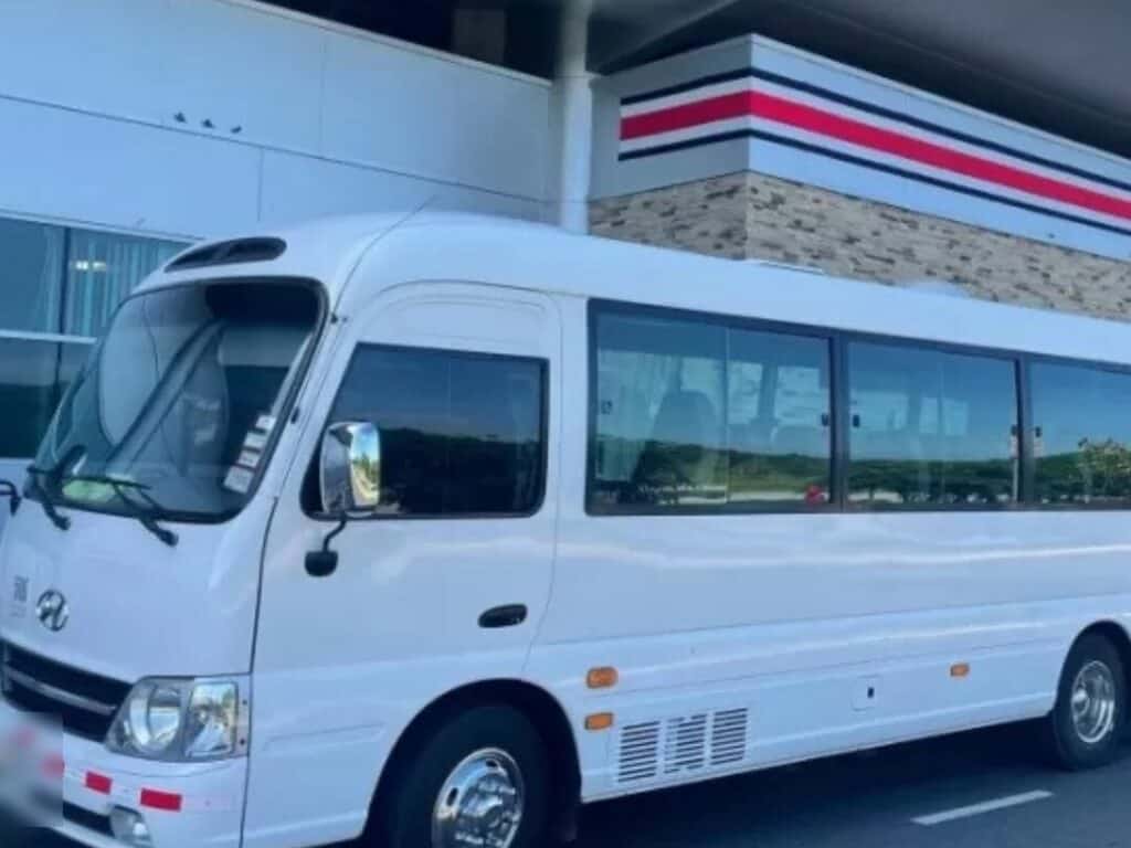 White shuttle minibus parked outside an airport terminal